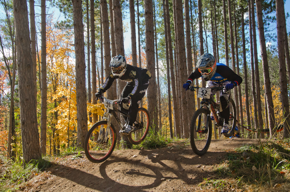 Dual slalom MTB racers air over jump head-to-head at the Michigan Tech Trails